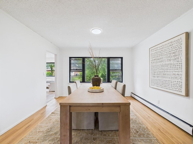 811 Bellmore Ave, East Meadow, NY 11554 - dining area featuring baseboard heating, light wood finished floors, and a textured ceiling