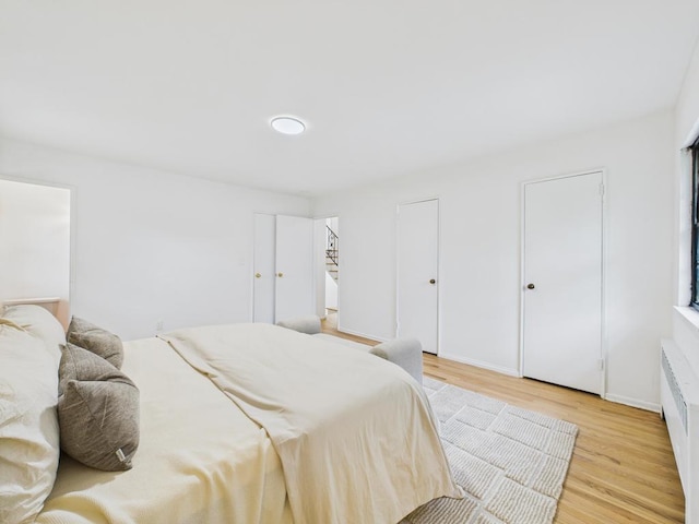 811 Bellmore Ave, East Meadow, NY 11554 - bedroom featuring light wood finished floors, radiator heating unit, and multiple closets