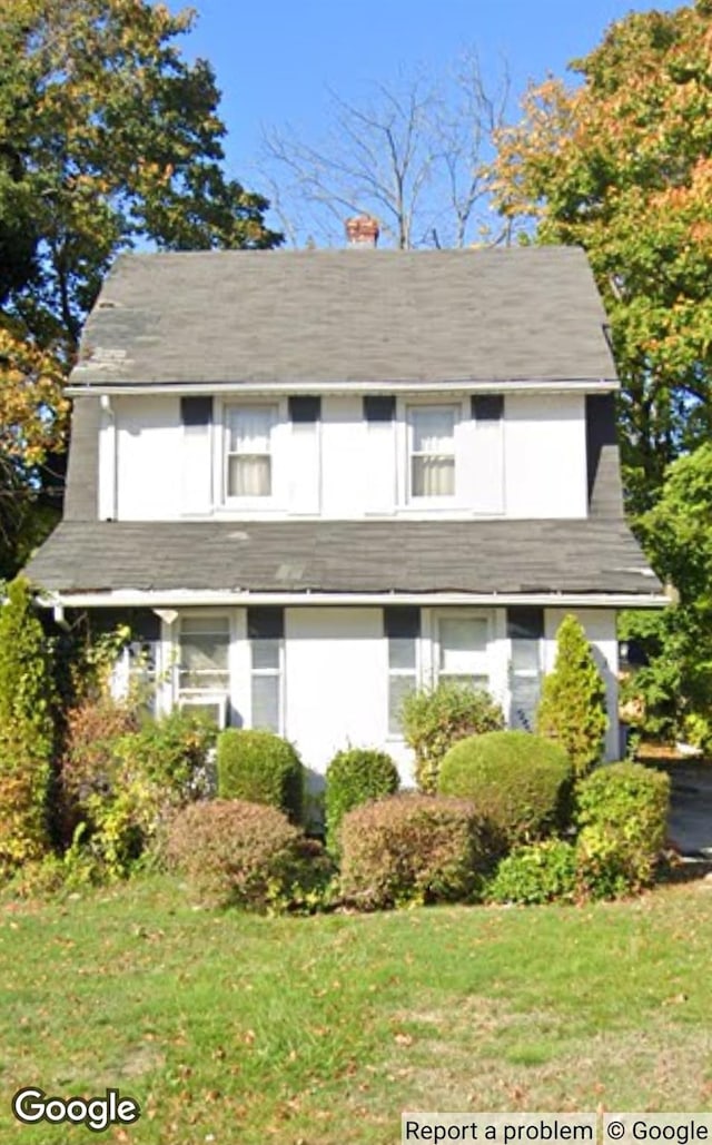 33 Willow Ave, Freeport, NY 11520 - view of front facade featuring a chimney, a front lawn, and a shingled roof