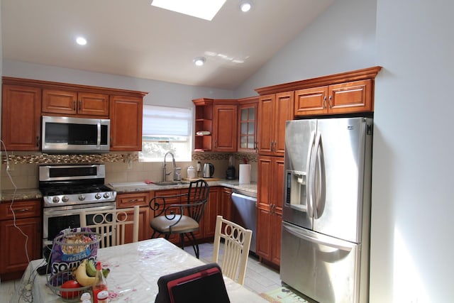242 W Centennial Ave, Roosevelt, NY 11575 - kitchen with appliances with stainless steel finishes, decorative backsplash, vaulted ceiling, recessed lighting, and brown cabinetry