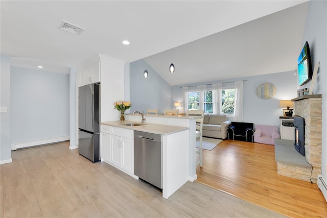75 Lynncliff Rd, Hampton Bays, NY 11946 - kitchen with stainless steel appliances, a baseboard radiator, open floor plan, a stone fireplace, and light wood-style floors
