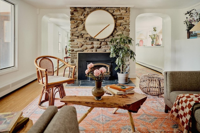 169 Mountain Rd, Cornwall On Hudson, NY 12520 - living area featuring baseboard heating, arched walkways, wood finished floors, a stone fireplace, and plenty of natural light