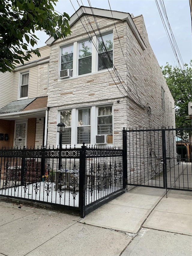 9721 83rd St, Ozone Park, NY 11416 - view of front of home with stone siding, a fenced front yard, a gate, and cooling unit