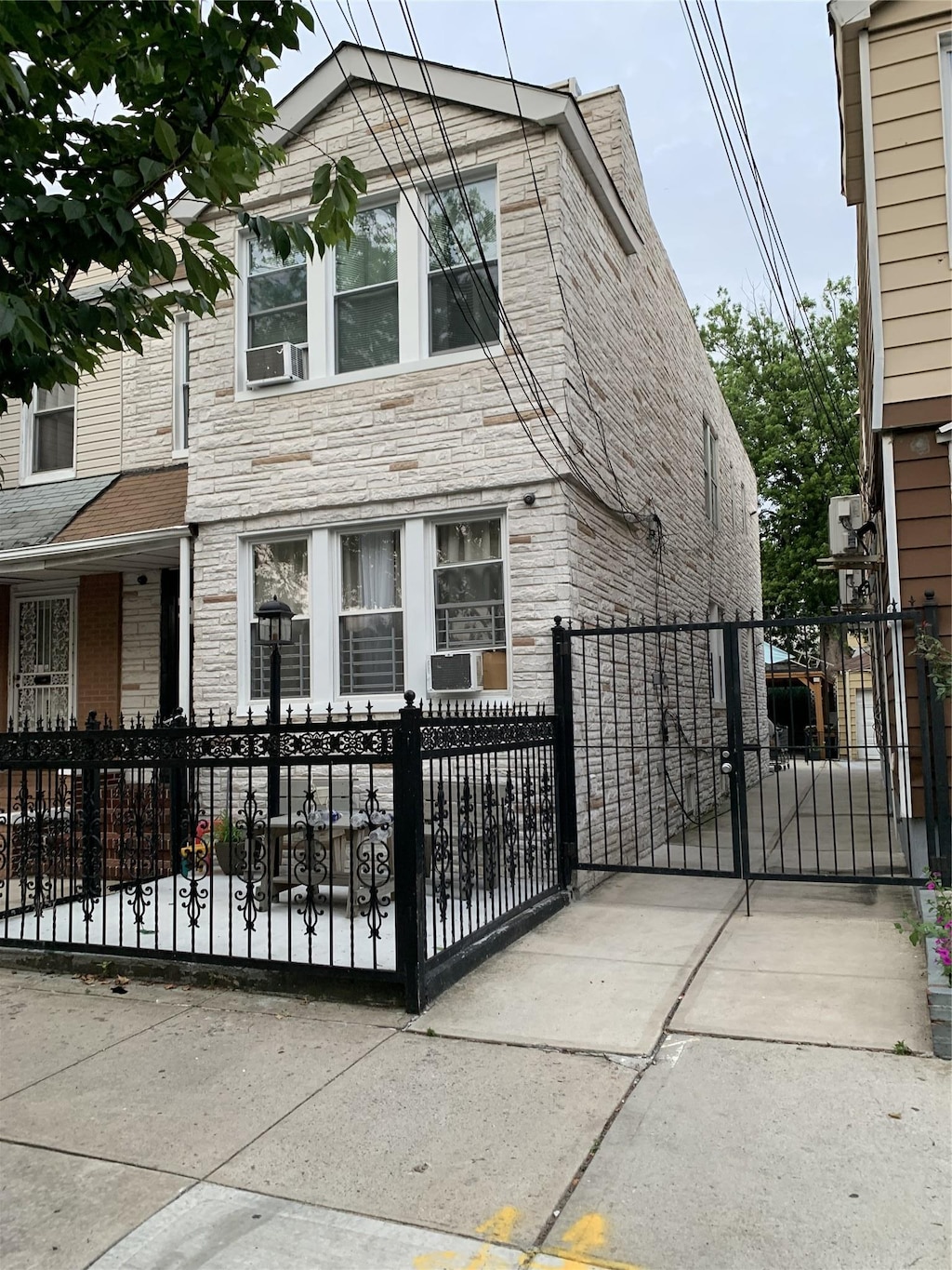 9721 83rd St, Ozone Park, NY 11416 - view of front of house with stone siding, a gate, and a fenced front yard