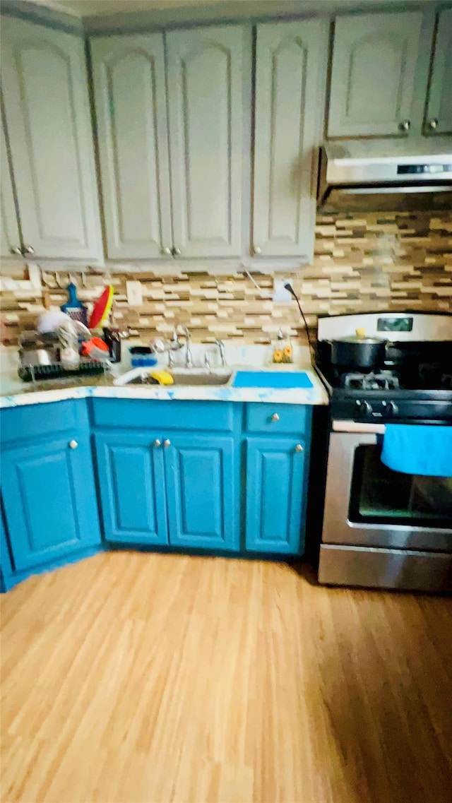 54-08 92nd St, Elmhurst, NY 11373 - kitchen with gas stove, blue cabinetry, range hood, light countertops, and light wood finished floors