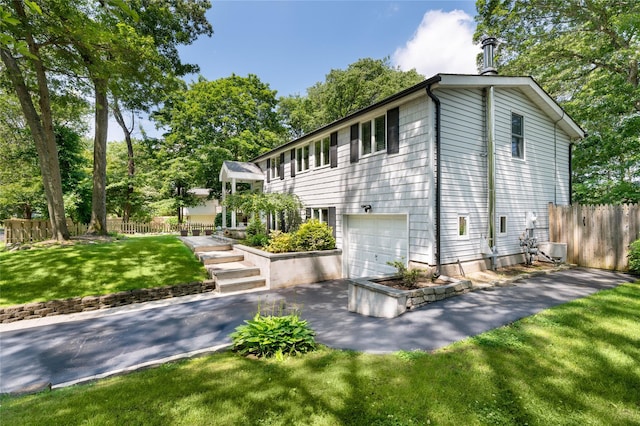 22 Woodchuck Ln, East Setauket, NY 11733 - view of side of home with an attached garage, asphalt driveway, and view of wooded area