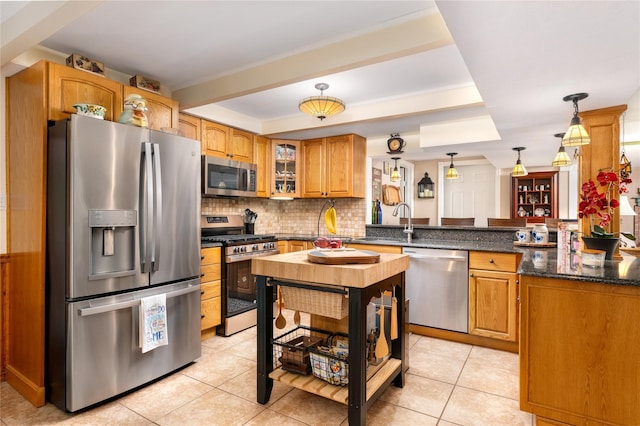 22 Woodchuck Ln, East Setauket, NY 11733 - kitchen featuring appliances with stainless steel finishes, a peninsula, backsplash, glass insert cabinets, and light tile patterned floors