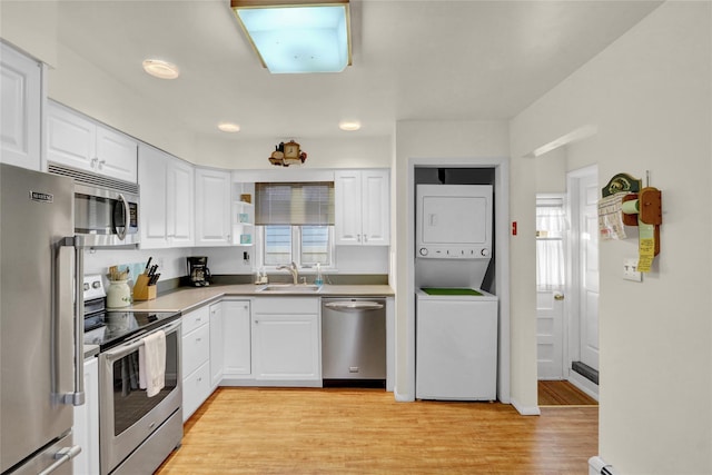 138 Sequams Ln E, West Islip, NY 11795 - kitchen with stainless steel appliances, stacked washing machine and dryer, healthy amount of natural light, and white cabinetry