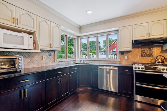17 Sterling Dr, Lake Grove, NY 11755 - kitchen featuring appliances with stainless steel finishes, ornamental molding, under cabinet range hood, dark wood finished floors, and dark stone counters