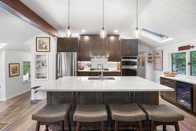 42 Raspberry Ln, Carmel, NY 10512 - kitchen featuring stainless steel appliances, a skylight, wine cooler, dark brown cabinetry, and vaulted ceiling