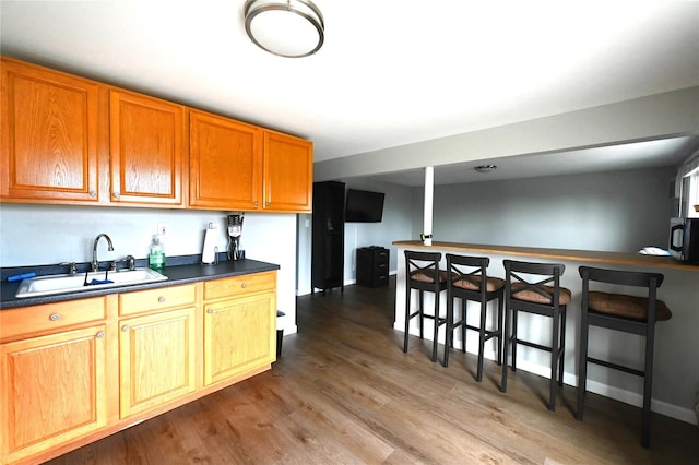 184 Sumpwams Ave, Babylon, NY 11702 - kitchen featuring dark countertops, wood finished floors, brown cabinets, and a breakfast bar