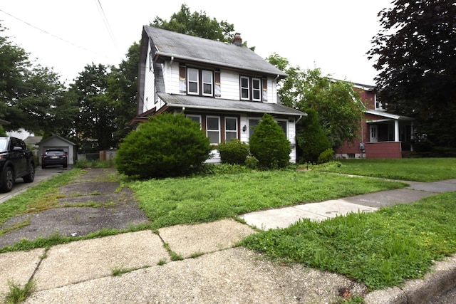 24 Parsons Dr, Hempstead, NY 11550 - view of front of property featuring a chimney, asphalt driveway, a front lawn, a garage, and an outdoor structure