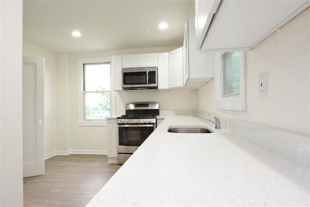 24 Parsons Dr, Hempstead, NY 11550 - kitchen featuring appliances with stainless steel finishes, white cabinetry, light wood-style flooring, and recessed lighting