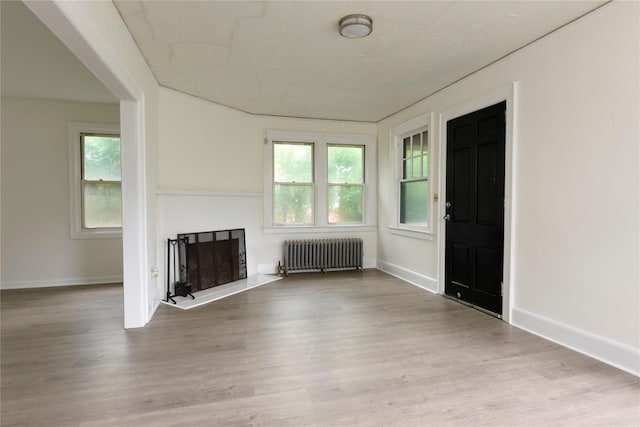 24 Parsons Dr, Hempstead, NY 11550 - unfurnished living room featuring radiator heating unit, a fireplace, and wood finished floors