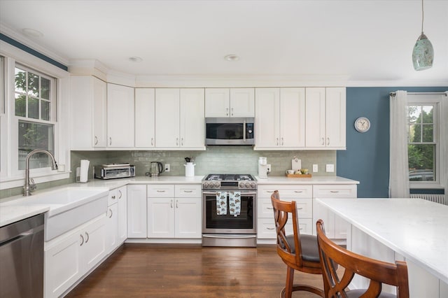 3665 Lufberry Ave, Wantagh, NY 11793 - kitchen with stainless steel appliances, light countertops, backsplash, white cabinets, and dark wood-type flooring