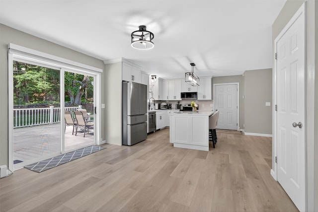97 Pittaluga Dr, Monticello, NY 12701 - kitchen featuring appliances with stainless steel finishes, light wood-style flooring, light countertops, white cabinetry, and a breakfast bar area