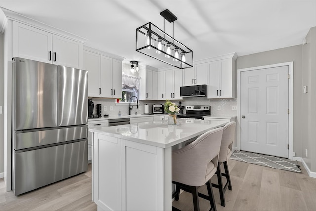97 Pittaluga Dr, Monticello, NY 12701 - kitchen featuring stainless steel appliances, light wood-style flooring, white cabinets, light countertops, and a kitchen island