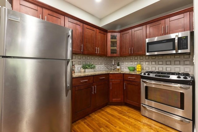 100 Ralph Ave Unit 2L, Brooklyn, NY 11221 - kitchen with appliances with stainless steel finishes, light wood finished floors, glass insert cabinets, light stone counters, and tasteful backsplash