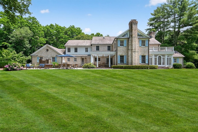 8 Danton Ln S, Locust Valley, NY 11560 - rear view of house with a chimney, a patio area, a yard, and a balcony