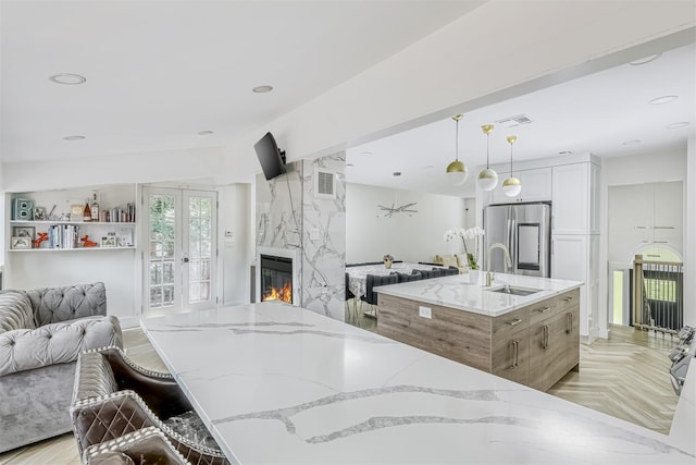 17 Onderdonk Rd, Suffern, NY 10901 - kitchen featuring stainless steel refrigerator, open floor plan, a high end fireplace, light stone countertops, and decorative light fixtures