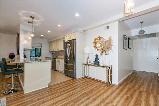 171 S Middle Neck Rd Unit 1F, Great Neck, NY 11021 - kitchen featuring appliances with stainless steel finishes, light wood finished floors, recessed lighting, light stone countertops, and a breakfast bar