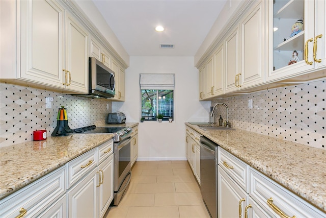 171 S Middle Neck Rd Unit 1F, Great Neck, NY 11021 - kitchen with stainless steel appliances, light tile patterned floors, backsplash, light stone counters, and glass insert cabinets