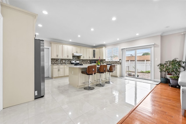 5 Vera Ave, Plainview, NY 11803 - kitchen with cream cabinets, crown molding, stainless steel appliances, under cabinet range hood, and decorative backsplash