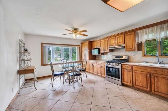 3 Washington Ave, Selden, NY 11784 - kitchen with stainless steel range with gas stovetop, under cabinet range hood, decorative backsplash, light countertops, and a ceiling fan
