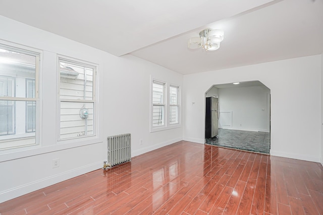 592 E 39th St, Brooklyn, NY 11203 - spare room with radiator heating unit, arched walkways, wood finished floors, and a chandelier