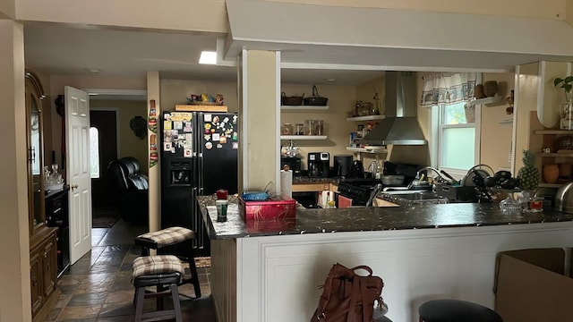 31 N Wayne Ave, West Haverstraw, NY 10993 - kitchen featuring wall chimney exhaust hood, black fridge with ice dispenser, dark stone finish floors, open shelves, and dark countertops