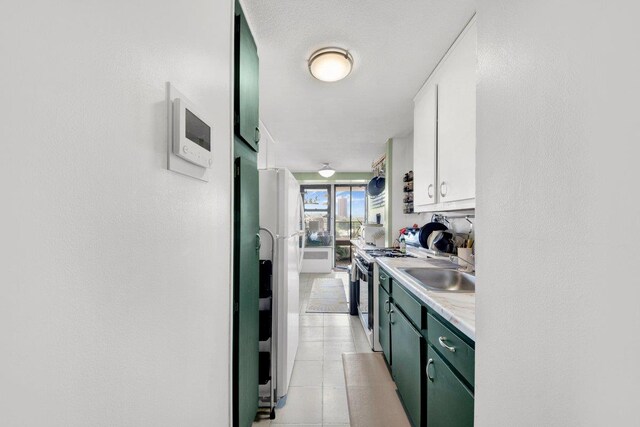290 W 232nd St Unit 8E, Bronx, NY 10463 - kitchen with gas range oven, white cabinetry, freestanding refrigerator, light countertops, and light tile patterned floors