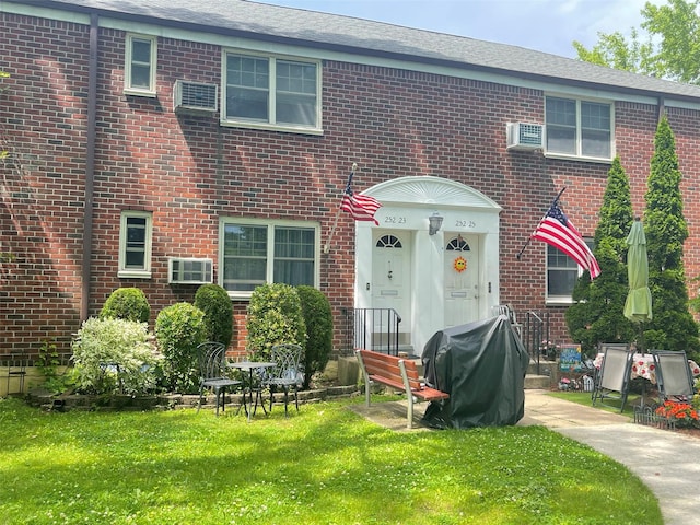 252-23 63rd Ave Unit 1Fl, Little Neck, NY 11362 - view of front of house featuring brick siding, a front yard, and an AC wall unit