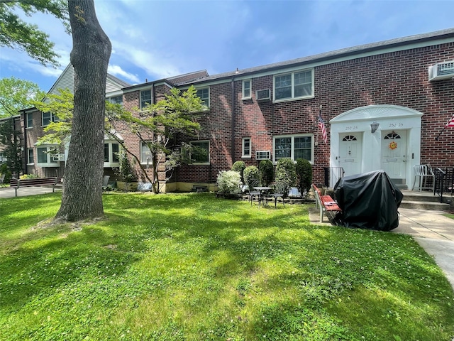 252-23 63rd Ave Unit 1Fl, Little Neck, NY 11362 - rear view of property with brick siding, a yard, and a wall unit AC