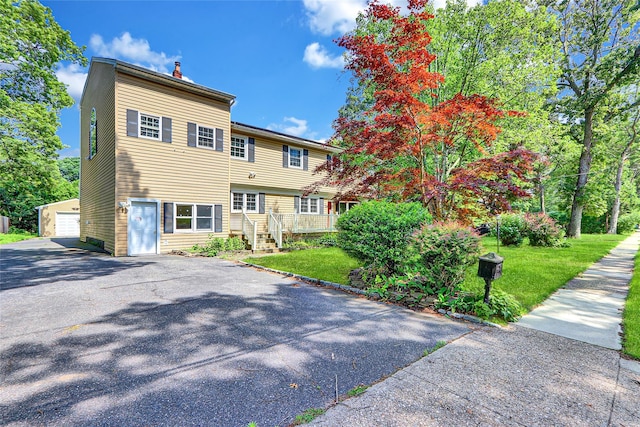89 Circuit Rd, Bellport, NY 11713 - view of front facade featuring a chimney, a front lawn, an outbuilding, and a garage