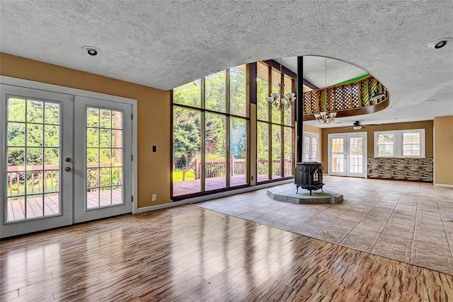 89 Circuit Rd, Bellport, NY 11713 - unfurnished living room with a wood stove, wood finished floors, a textured ceiling, french doors, and a ceiling fan