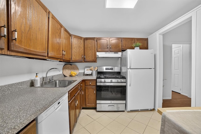 13 Scenic Unit J, Croton-On-Hudson, NY 10520 - kitchen featuring white appliances, under cabinet range hood, brown cabinets, light tile patterned floors, and a skylight