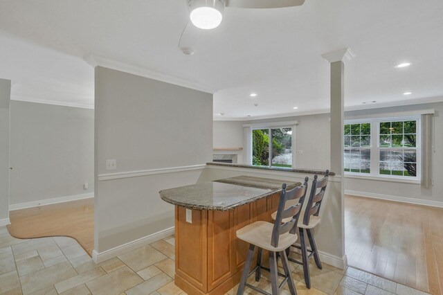 86 Erik Dr, East Setauket, NY 11733 - kitchen with dark stone countertops, crown molding, open floor plan, a breakfast bar area, and recessed lighting