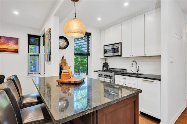 9707 4th Ave Unit 3R, Brooklyn, NY 11209 - kitchen featuring appliances with stainless steel finishes, decorative backsplash, white cabinetry, recessed lighting, and wood finished floors