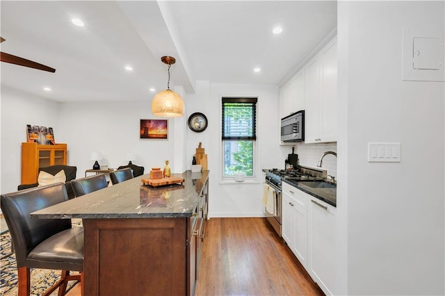 9707 4th Ave Unit 3R, Brooklyn, NY 11209 - kitchen featuring stainless steel appliances, a kitchen bar, wood finished floors, tasteful backsplash, and recessed lighting