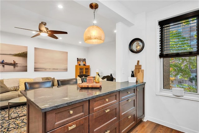 9707 4th Ave Unit 3R, Brooklyn, NY 11209 - kitchen featuring wood finished floors, dark stone counters, a ceiling fan, open floor plan, and hanging light fixtures
