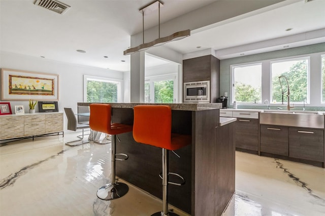 140 Old Farm Rd S, Pleasantville, NY 10570 - kitchen with a center island, a breakfast bar, modern cabinets, dark brown cabinets, and stainless steel microwave