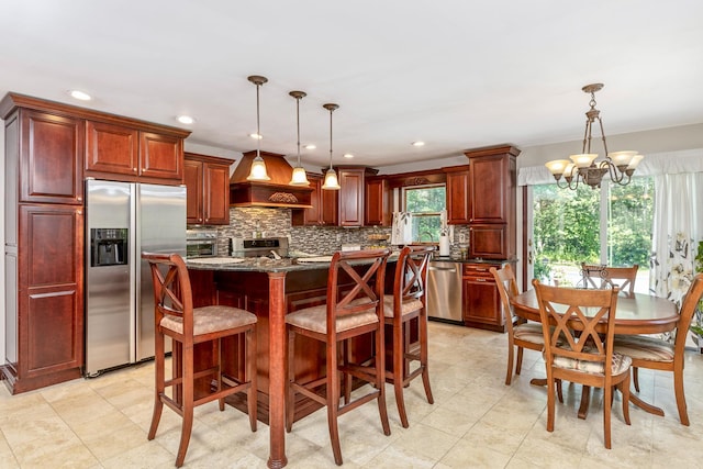 113 Pine St, Port Jefferson Station, NY 11776 - kitchen featuring stainless steel appliances, premium range hood, reddish brown cabinets, a chandelier, and recessed lighting