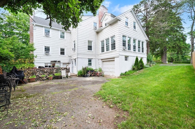 1146 N Ave, New Rochelle, NY 10804 - back of house featuring a chimney, asphalt driveway, an attached garage, and a lawn