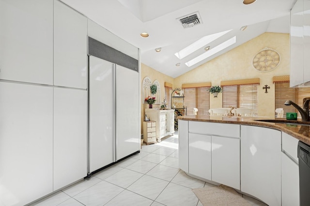 2092 Vine Dr, Merrick, NY 11566 - kitchen with white built in fridge, a skylight, white cabinets, light tile patterned floors, and dishwasher