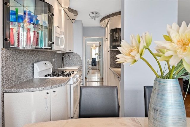 2928 W 5th St Unit 10P, Brooklyn, NY 11224 - kitchen with white appliances, tasteful backsplash, white cabinetry, and light countertops