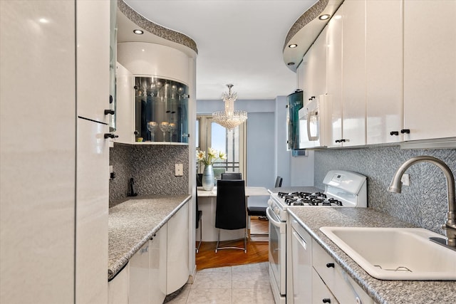 2928 W 5th St Unit 10P, Brooklyn, NY 11224 - kitchen with white appliances, tasteful backsplash, white cabinetry, a chandelier, and recessed lighting