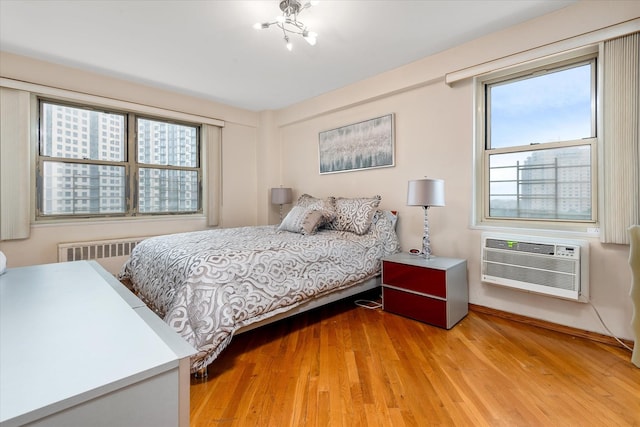 2928 W 5th St Unit 10P, Brooklyn, NY 11224 - bedroom with radiator, light wood-style flooring, a wall mounted AC, and a chandelier