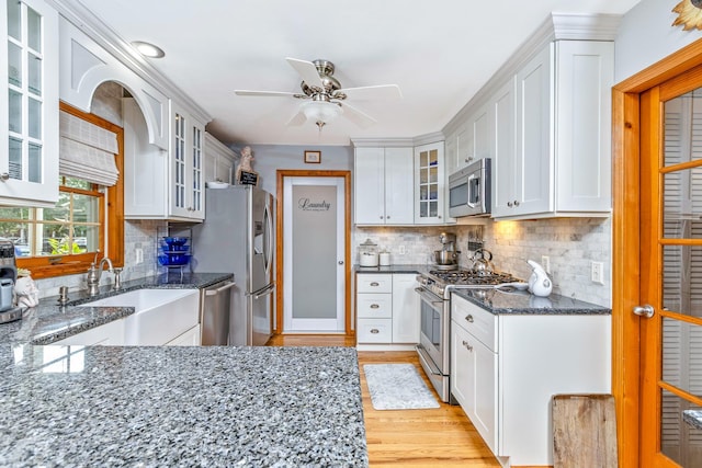 600 Shipyard Ln, East Marion, NY 11939 - kitchen with stainless steel appliances, light wood-type flooring, dark stone countertops, a ceiling fan, and white cabinetry