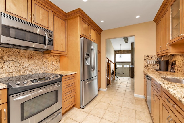 790 Adams St, Baldwin, NY 11510 - kitchen with stainless steel appliances, brown cabinets, light stone counters, light tile patterned floors, and recessed lighting