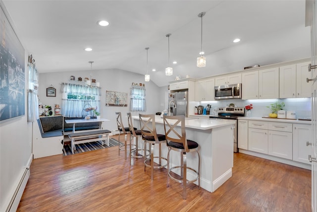 5 Fox Rd, Middle Island, NY 11953 - kitchen featuring appliances with stainless steel finishes, a baseboard heating unit, a kitchen breakfast bar, lofted ceiling, and light countertops